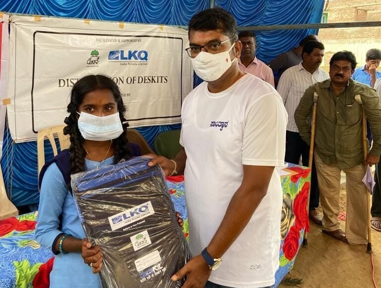 Handing over school bags and educational supplies to students.